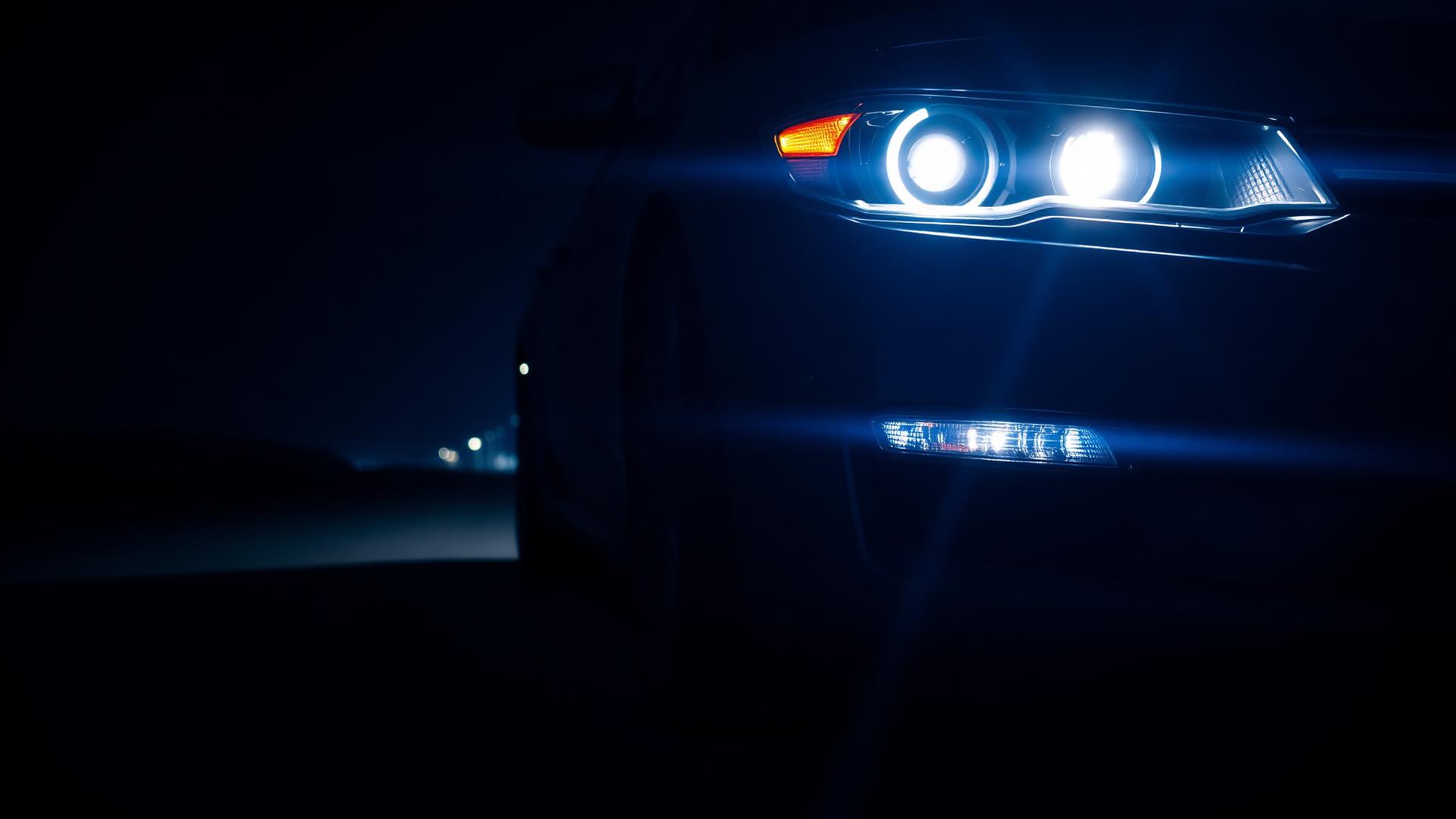 Carro com faróis restaurados iluminando a estrada à noite